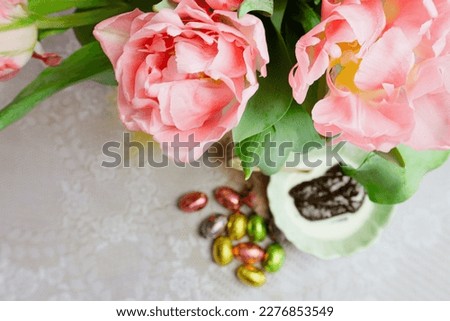 Pink tulips for easter, malted rye and Easter chocolate Eggs on table
