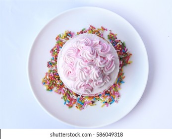 Pink Vanilla Cupcake. Vanilla Cake In Paper Cup Decorated White,pink Creamy And Colorful Sugar. Close Up Top View On A White Plate. Isolated On White Background.