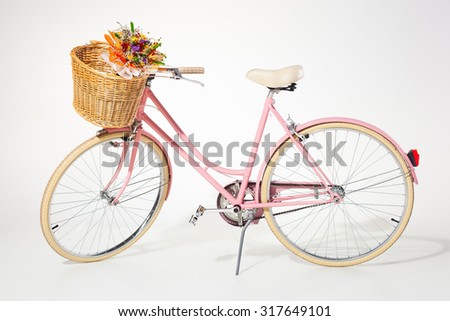pink vintage bicycle with flower basket isolated on white background