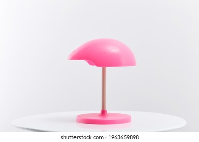 Pink Wig Stand On The Table Against A White Background.