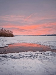 Pink Winter Sunset Over The Frozen Lake In A Snowy Day
