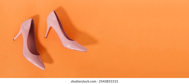 pink women's high-heeled shoes on a bright orangebackground. The concept of sales and advertising. flatly. From above. - Powered by Shutterstock