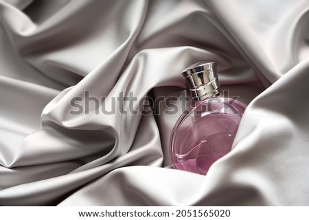 Pink women's perfume bottle in satin cloth draperies.