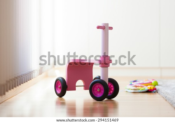 Pink wood\
bike toy in the middle of the living\
room