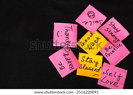 Pink and yellow paper cut notes with uplifting messages like "Smile," "Thanks," "I Love You," and "Be Happy" on a black background. Empty space for personalized text or designs.