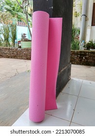 A Pink Yoga Mat Rolled Up Against The Wall