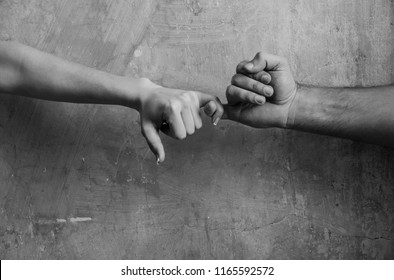 Pinkie promise and friendship. Male and female hands touching each other with little fingers on abstract cement wall on beige background - Shutterstock ID 1165592572