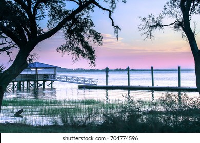 Pinkish purple Sunset at Bloody Pointe on Daufuskie Island, SC at a pier on a desolate island off the coast of South Carolina. Silhouette trees in foreground and a dock Daufuskie September sunset