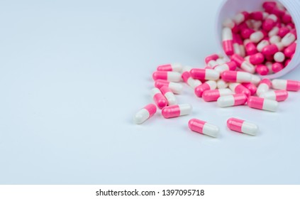 Pink-white capsule pills spread out of drug bottle. Antipsychotic drug. Capsule medicine for treatment depression. Anti-anxiety drug. Global healthcare. Pharmacy background. Pharmaceutical industry.