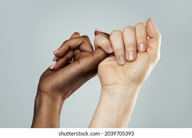 A pinky promise gesture between African and Caucasian women. Closeup of palms on gray background. Interracial friendship, care and support. - Shutterstock ID 2039705393