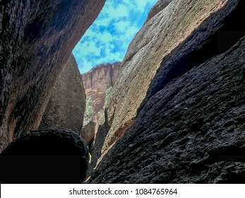 Pinnacles National Park, California. View from the inside of Balconies Cave with rocks from both side and the mountain view ahead under the blue sky with dreamy clouds. 