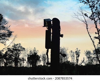 Pinocchio; Wooden Pinocchio Figure Is Like Climbing The Wood Pole With A Forest Silhouette And Sunset Background; It Is A Bird House
