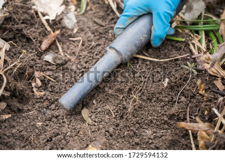 pinpointer metal detector in digger archaeologist hand and ancient coin. Search for precious old coins or metals with a pinpointer metal detector. Valuable historical find