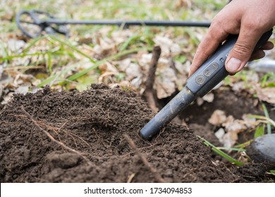 
pinpointer metal detector in digger hand and ancient coin. Search for precious old 
historical coins or metals with a pinpointer metal detector. Valuable 
archaeologist find