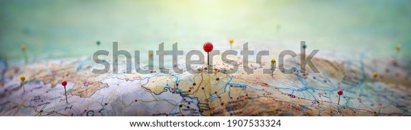 Pins on geographic map curved like mountains.
Pinning a location on map with mountains. Adventure, discovery,
navigation, geography, mountaineering, rock climbing, hike  and
travel concept background.
