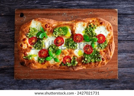 Pinsa Romana with mozzarella cheese and basil pesto on wooden table 