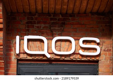 Pinsk, Belarus. Jun 2022. Sign IQOS. Company Modern Neon Signboard IQOS On Historic Red Brick Building. IQOS Of Philip Morris International - Boutique Of Heated Tobacco Smoking Devices