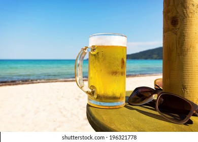 Pint Of Cold Beer On Top Of The Beach Table.