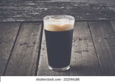 Pint Of Dark Beer On Wood Background With Vintage Film Style