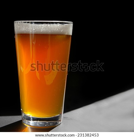 Pint glass of craft beer, backlit on black
