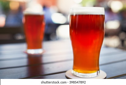 Pint Glass Of Craft Beer Indian Pale Ale On Wooden Table In Beer Garden