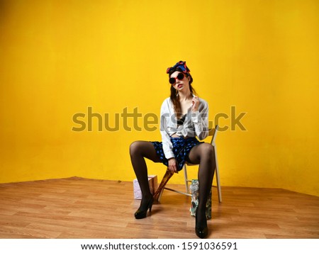 pin-up girl in a blue skirt on a chair on a yellow background