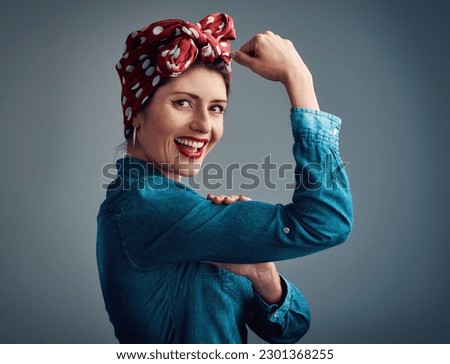 Pinup girl, strong and flexing muscle portrait in studio for beauty, women power and fashion. Happy female person show bicep on a grey background for motivation, freedom and retro or vintage style