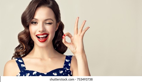 Pin-up retro girl with curly hair  winking, smiling and showing OK sign . Presenting your product. Expressive facial expressions
 - Shutterstock ID 753493738