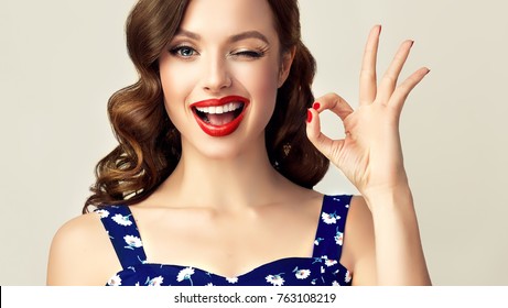 Pin-up retro girl with curly hair  winking, smiling and showing OK sign . Presenting your product. Expressive facial expressions - Shutterstock ID 763108219
