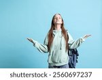 Pious woman looking up towards sky, waiting for sign from god. Spiritual girl doing worship hand gesturing, spreading arms, hoping for miracle, isolated over studio background