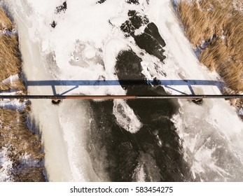 The Pipe Of The Factory Above Frozen River. Steal Big Pipeline. Aerial View.