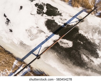 The Pipe Of The Factory Above Frozen River. Steal Big Pipeline. Aerial View.