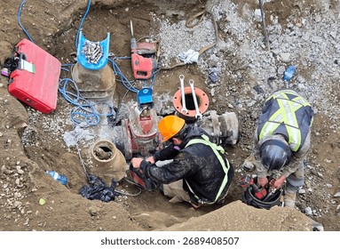 Pipe layers install new hydrant assembly with ductile iron fittings and flange connection inside trench during municipal watermain upgrade project.
