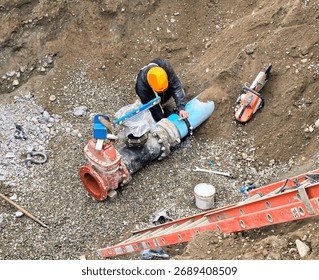 Pipe layers install new hydrant assembly with ductile iron fittings and flange connection inside trench during municipal watermain upgrade project.
