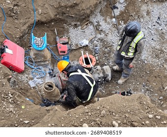 Pipe layers install new hydrant assembly with ductile iron fittings and flange connection inside trench during municipal watermain upgrade project.
