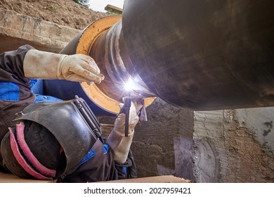 Pipe Welding. Construction Of A New Pre-insulated Hot Water Pipeline. Heating Network Repair. Welder At Work. Heat Distribution In The City. Blue Electric Welding Arc. 