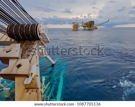 Pipelaying vessel with a pipeline stinger in the water during subsea pipeline construction/installation with an oil and gas platform in the vicinity - South China Sea, Malaysia