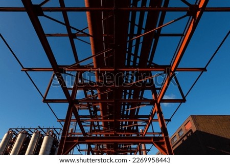 Pipeline bridge on the historic industrial site “Kokerei Zollverein“ in Essen Ruhr Basin Germany. Red steel construction on a sunny day from below. Coking plant buildings are tourist attraction today.