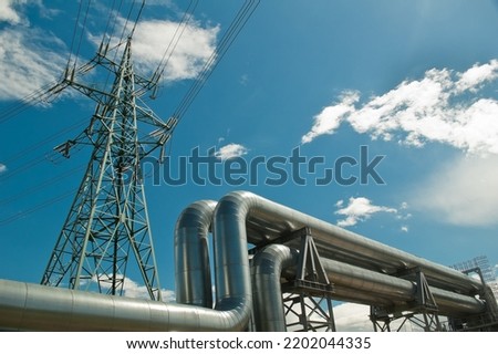 pipeline and power line support, in the photo pipeline and power line tower close-up against the background of blue sky and clouds.