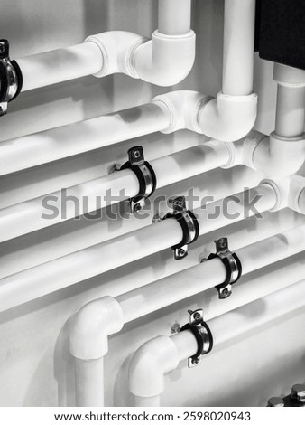 Pipes are arranged neatly along a wall with metal clamps securing them in place. The installation highlights precision and cleanliness in plumbing work, showcasing a modern aesthetic.
