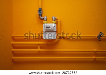 Pipes and gas-meter on orange wall