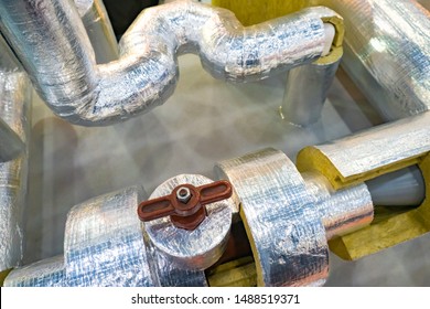 Pipes with a layer of insulating material and foil. Pipes with brown valve. Foil insulation for pipes. Demonstration of thermal insulation properties of insulation with foil. 