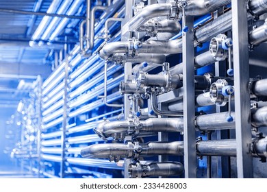 Pipes stainless steel brewing equipment, large reservoirs or tanks in modern beer factory. Brewery production concept, industrial blue background.