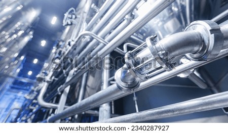 Pipes stainless steel brewing equipment, large reservoirs or tanks in modern beer factory. Brewery production concept, industrial blue background.