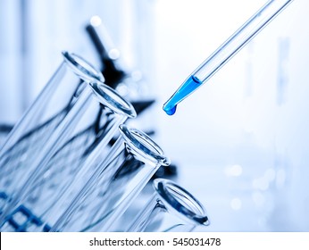Pipette adding fluid to one of several test tubes .medical glassware