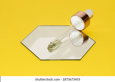 Pipette Dropper With Retinol Beauty Oil On A Mirror Hexagon On Illuminating Yellow Background With Focus On Pipette