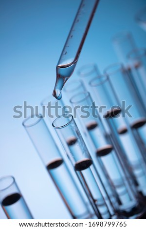 Pipette dropping a sample into a test tube. Science and laboratory concept.