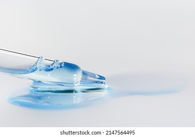 Pipette with fluid hyaluronic acid on blue background. Cosmetics and healthcare concept closeup. Dose of serum, retinol with air bubbles. Flat lay. Luxury beauty product presentation, macro