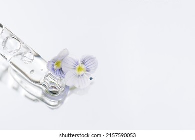 Pipette With Transparent Liquid On White Glass Background With Copy Space. Texture Of Face Serum Or Cosmetic Oil. Selective Focus, Macro Photo