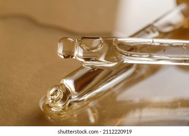 Pipettes with oil or serum on a golden background.